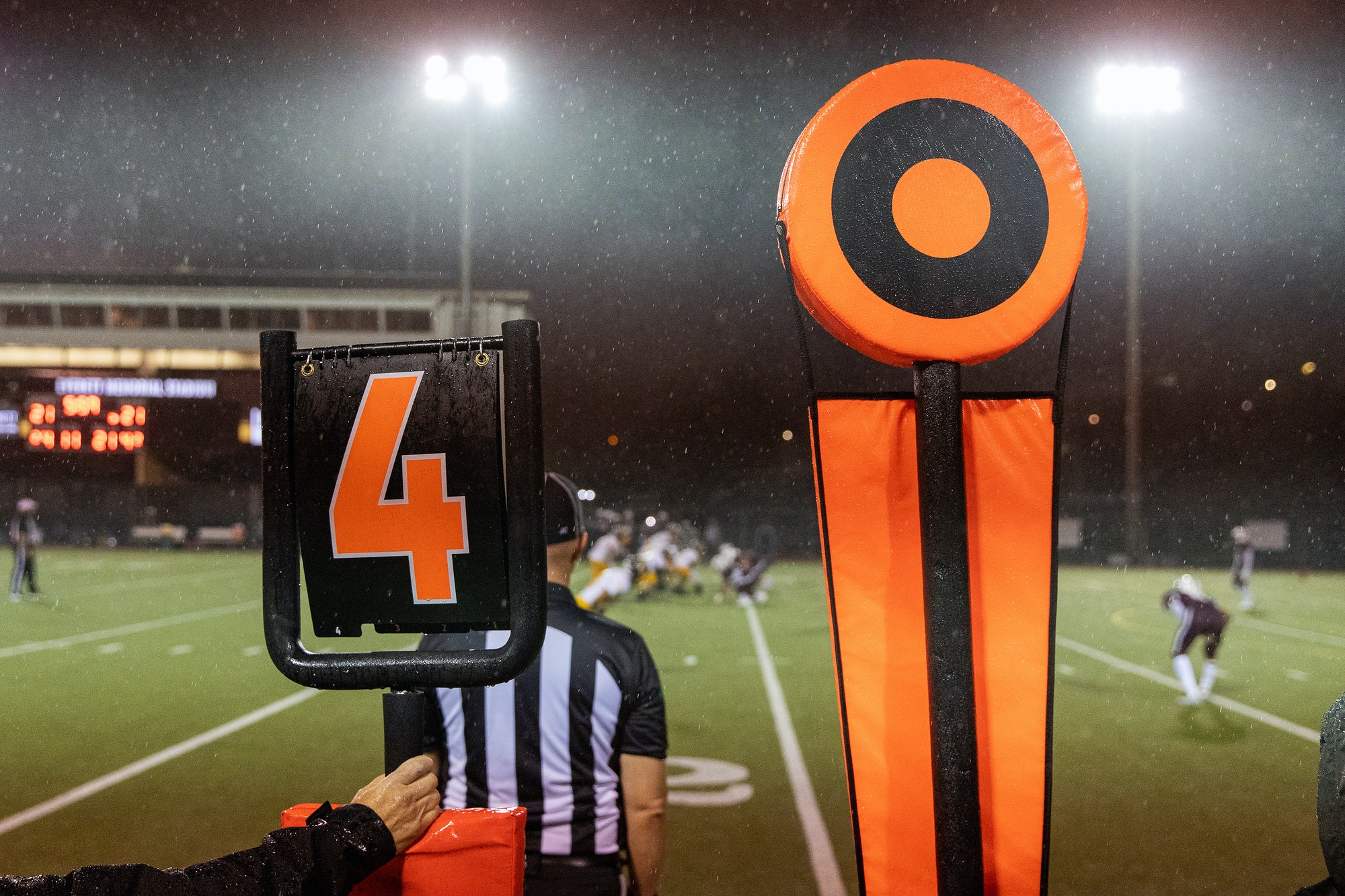 American football fourth down marker behind referee on rainy game day sideline on the field