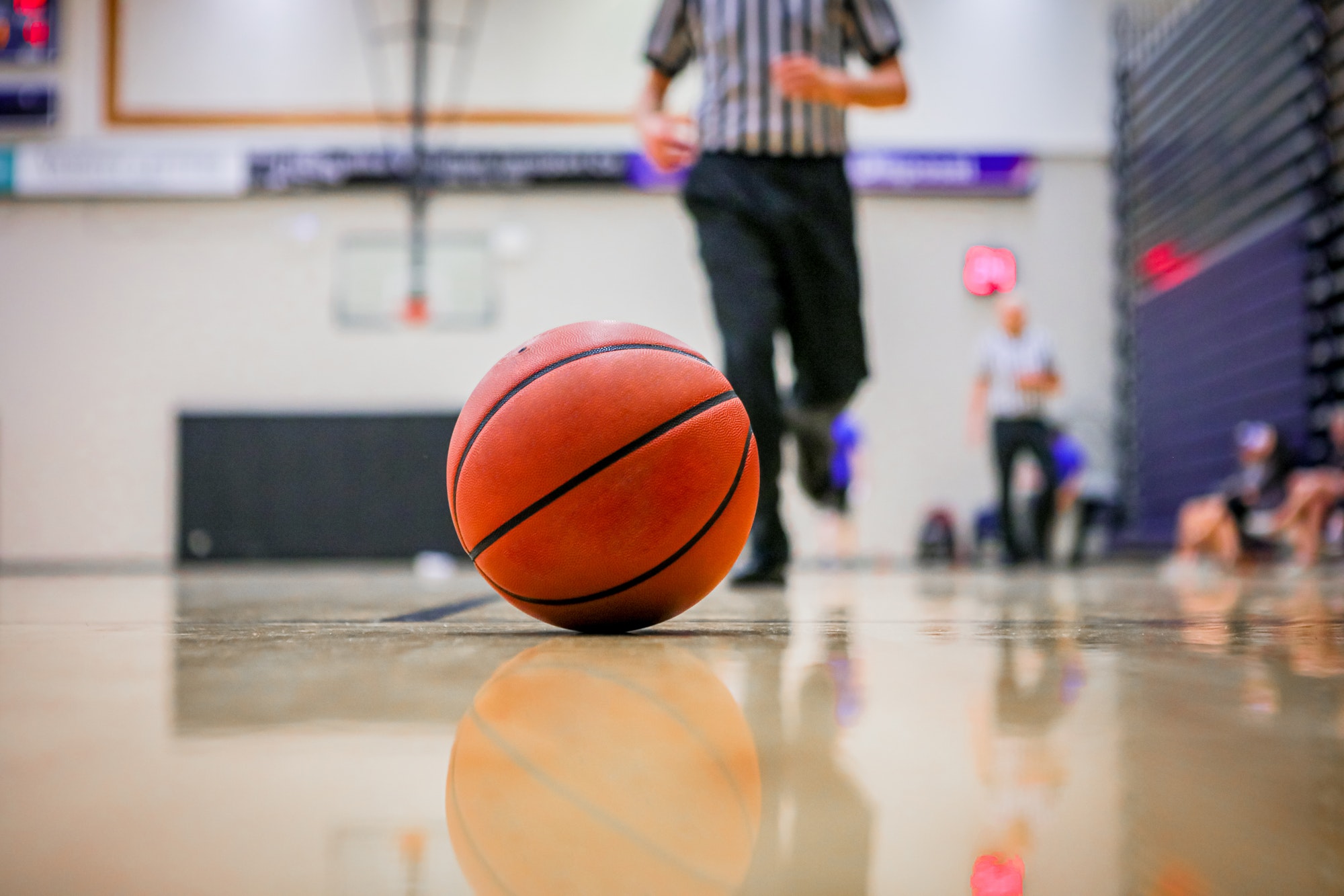 Selective focus shot of a basketball rolling in the hardcourt referee